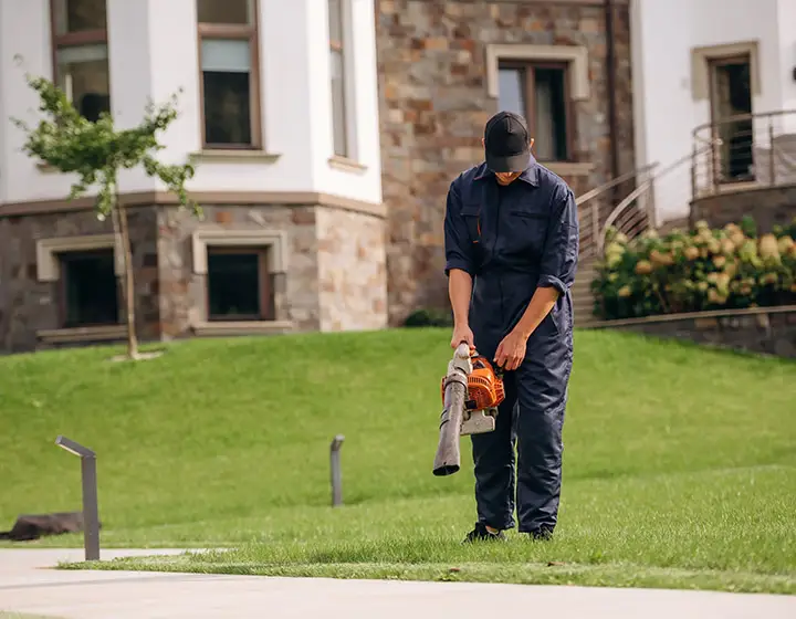 Ein Mitarbeiter mit Laubbläser bei der Grünflächenpflege
